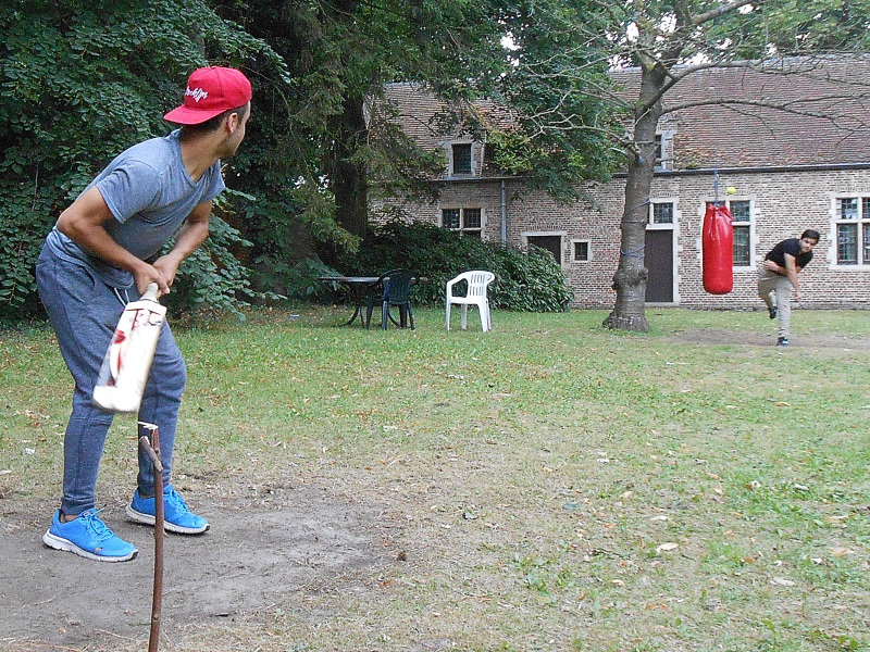 twee jongens spelen cricket in de tuin van een abdij