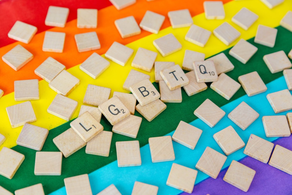 LGBTQ in scrabble letters over een regenboogvlag