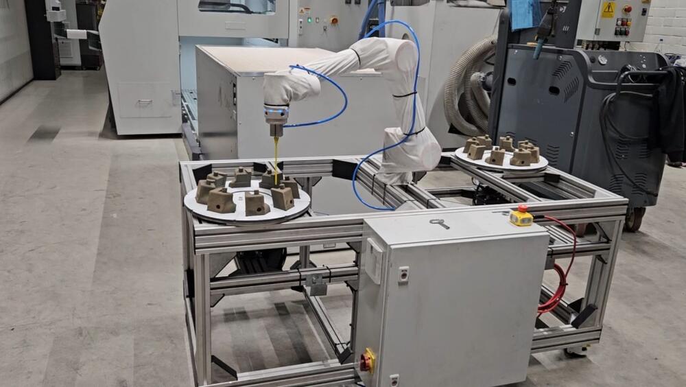 De installatie in werking: de cobot blaast de zandkernen schoon terwijl de draaitafels ze presenteren.