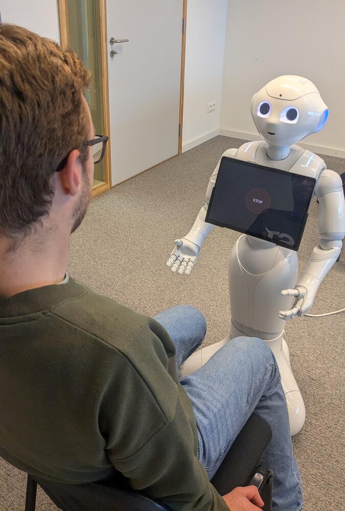 Een student die praat met de humanoïde robot Pepper.