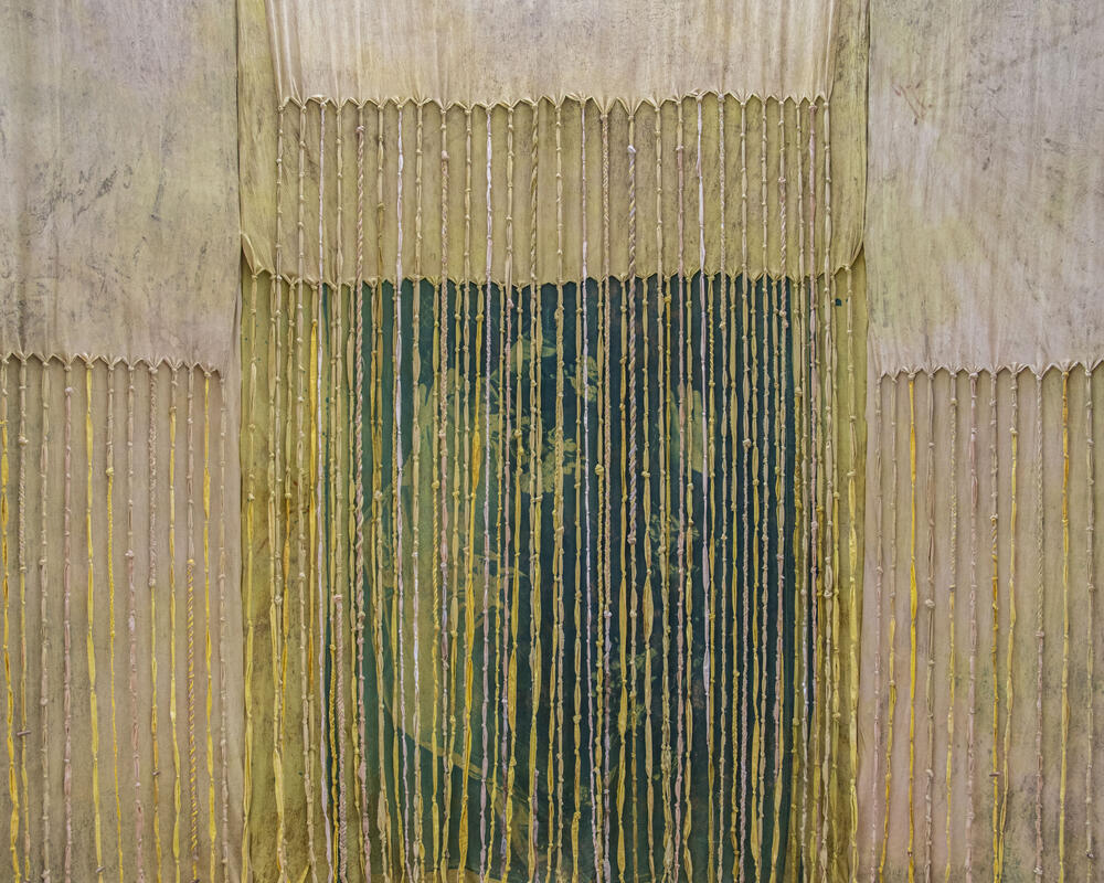 Binnenzicht van De zoete afstand, met melhfa's geverfd met henna en de cyanotypefoto van Yasmins biddende mama. Foto: Yasmin Gheisari.