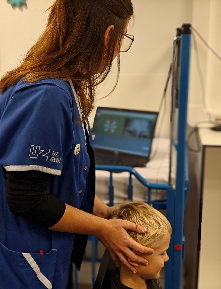 The image shows a person dressed in a blue uniform, assisting a child by checking their head using a medical device.</p>
<p>AI-generated content may be incorrect.